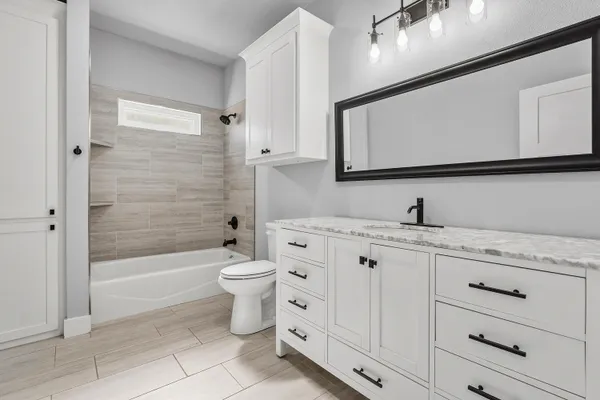 a bathroom with a granite countertop toilet sink and mirror