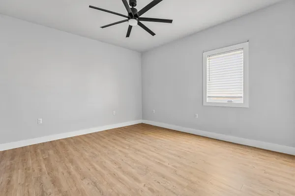 an empty room with a window and a fan