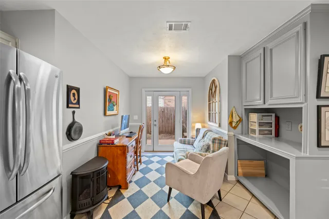 a living room with furniture a flat screen tv and a refrigerator