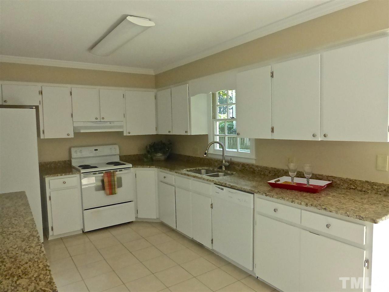 8333 Apple Orchard Way Raleigh, NC 27615 - Photo 18 of 25 a kitchen with granite countertop white cabinets and white appliances