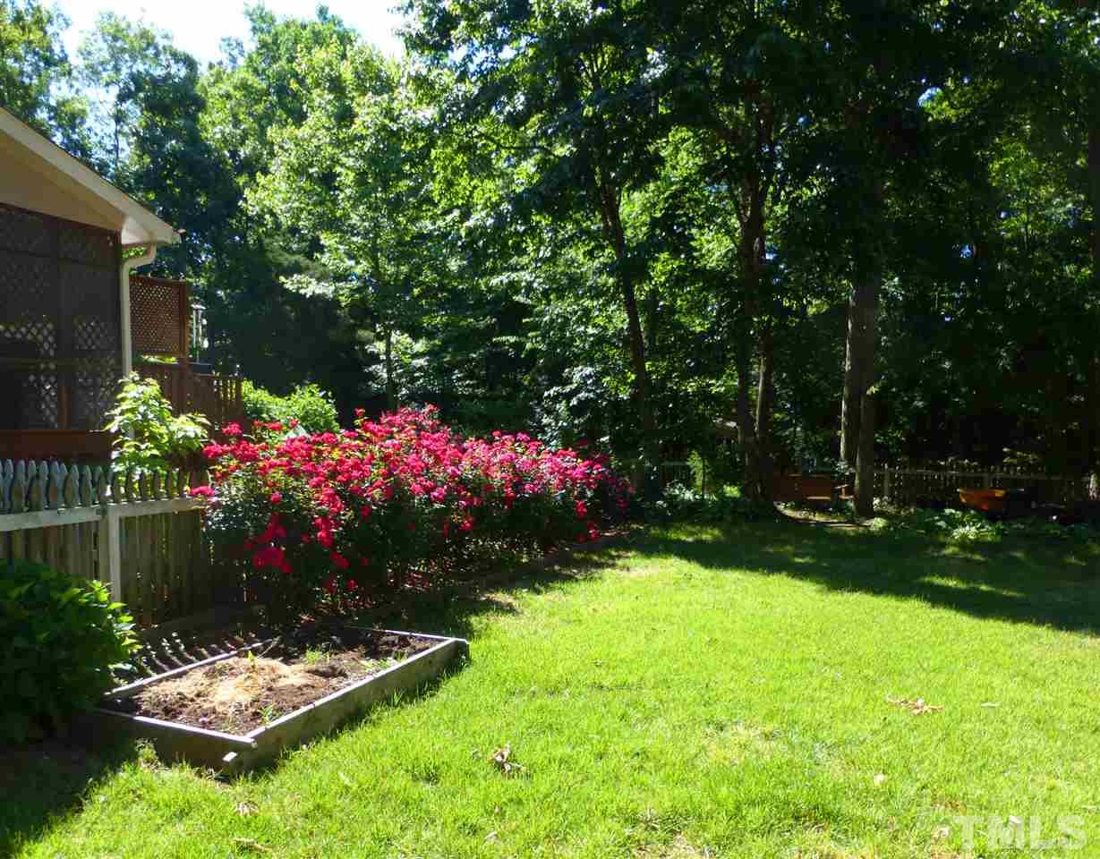 8333 Apple Orchard Way Raleigh, NC 27615 - Photo 3 of 25 a view of a garden with flowers and a bench