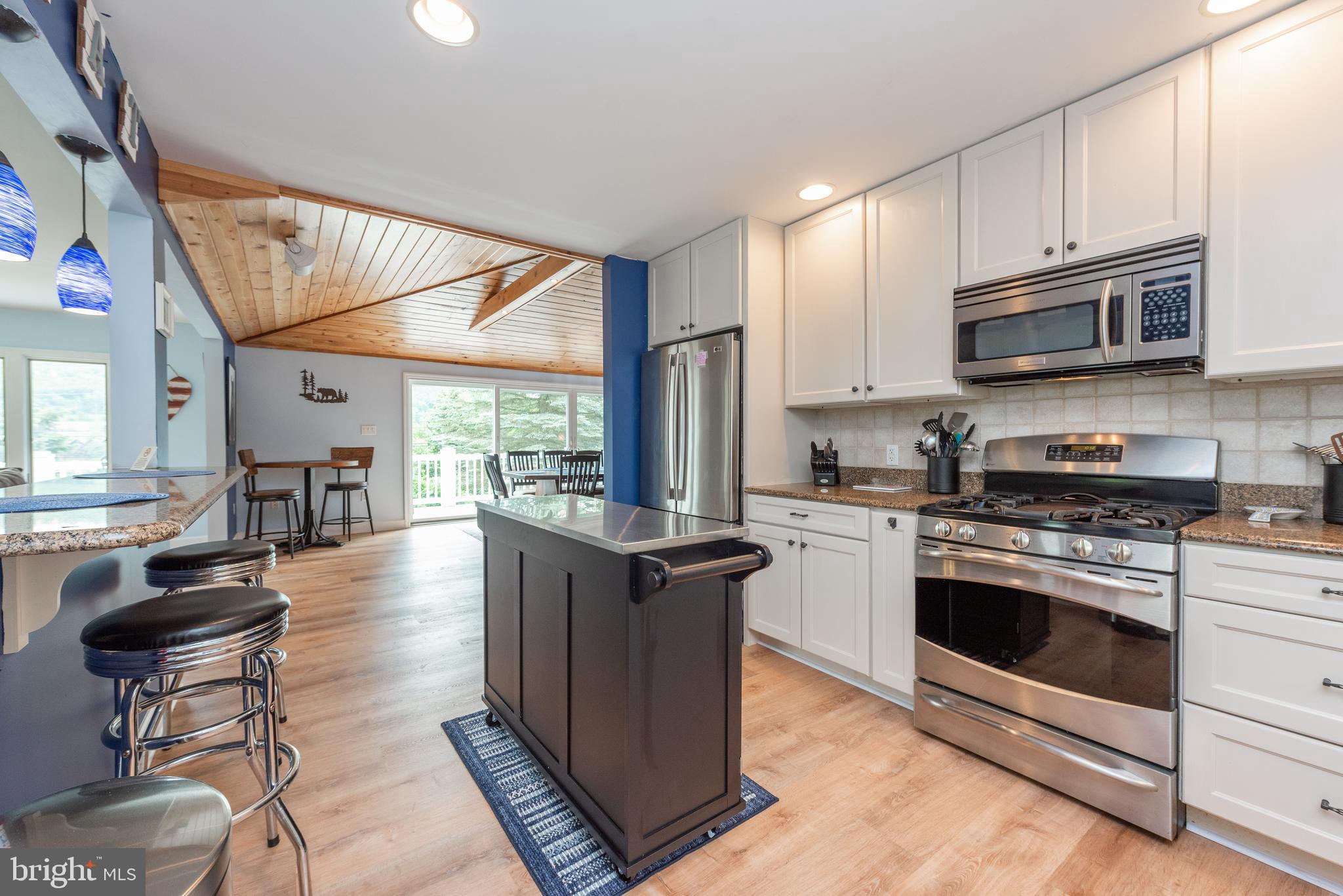 926 Marsh Hill Road McHenry, MD 21541 - Photo 11 of 70 a kitchen with stainless steel appliances granite countertop a stove top oven a sink dishwasher a dining table and chairs with wooden floor