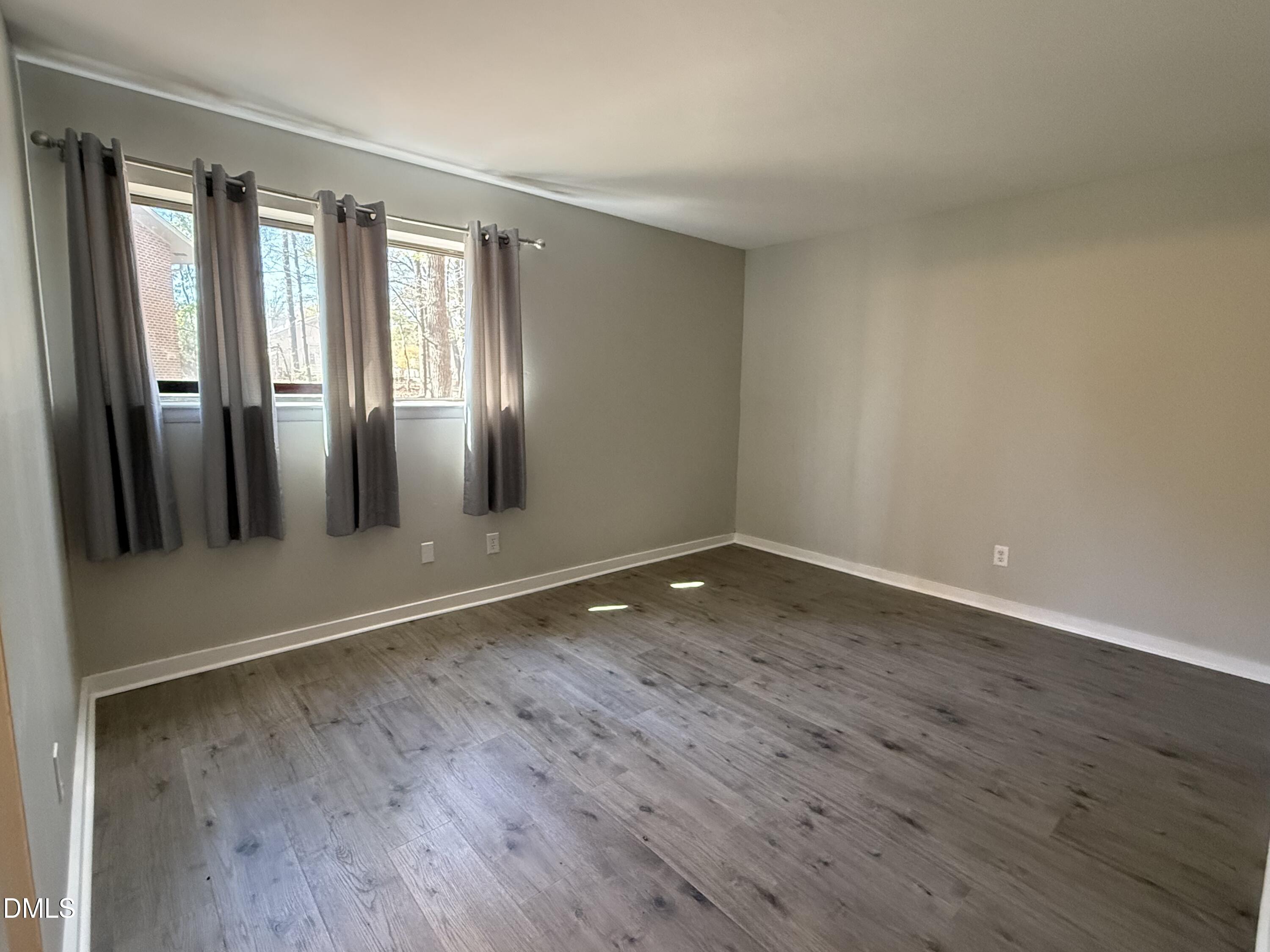 1295 Schaub Drive, Unit C Raleigh, NC 27606 - Photo 11 of 15 a view of an empty room with wooden floor and a window