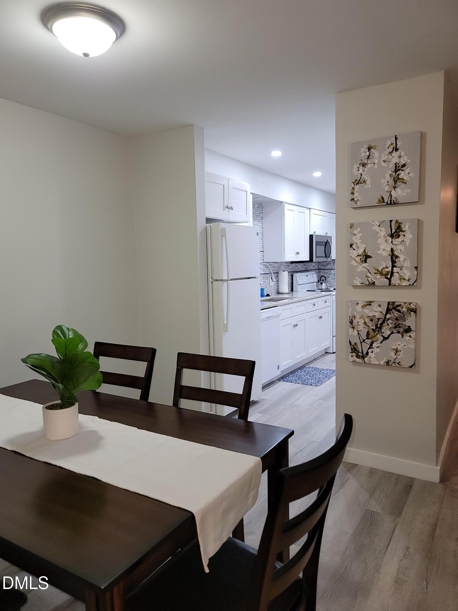 1295 Schaub Drive, Unit C Raleigh, NC 27606 - Photo 4 of 15 a kitchen with stainless steel appliances kitchen island a table and chairs in it