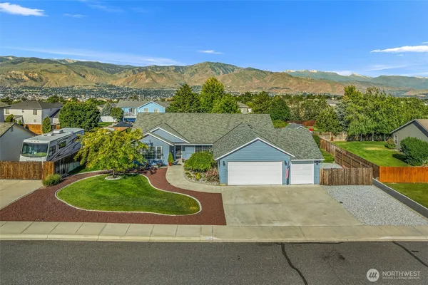 a view of a house with a yard and mountain view in back
