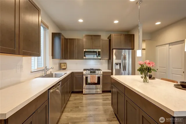 a kitchen with stainless steel appliances granite countertop sink stove refrigerator and cabinets
