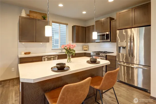 a kitchen with a refrigerator a stove a sink and white cabinets with wooden floor