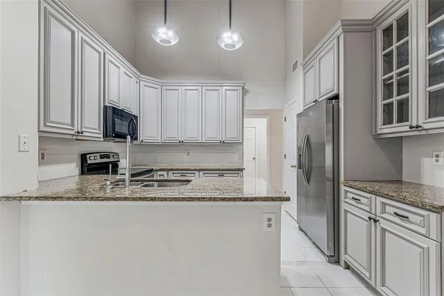 a kitchen with stainless steel appliances granite countertop a refrigerator a stove and a sink