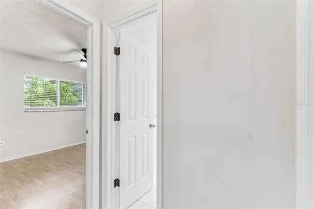 a view of a hallway with wooden floor and a bathroom