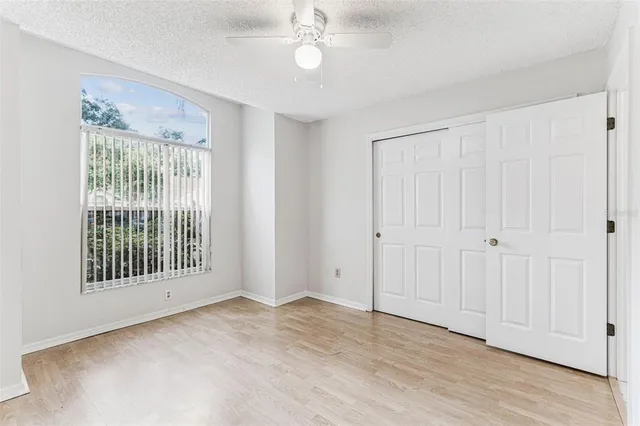 an empty room with wooden floor fireplace and windows