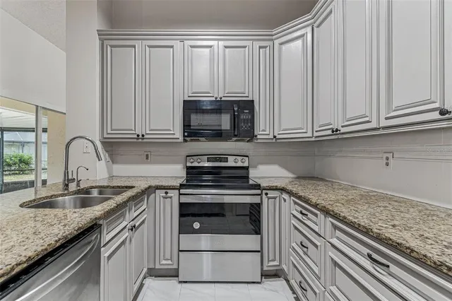 a kitchen with granite countertop a stove sink and refrigerator