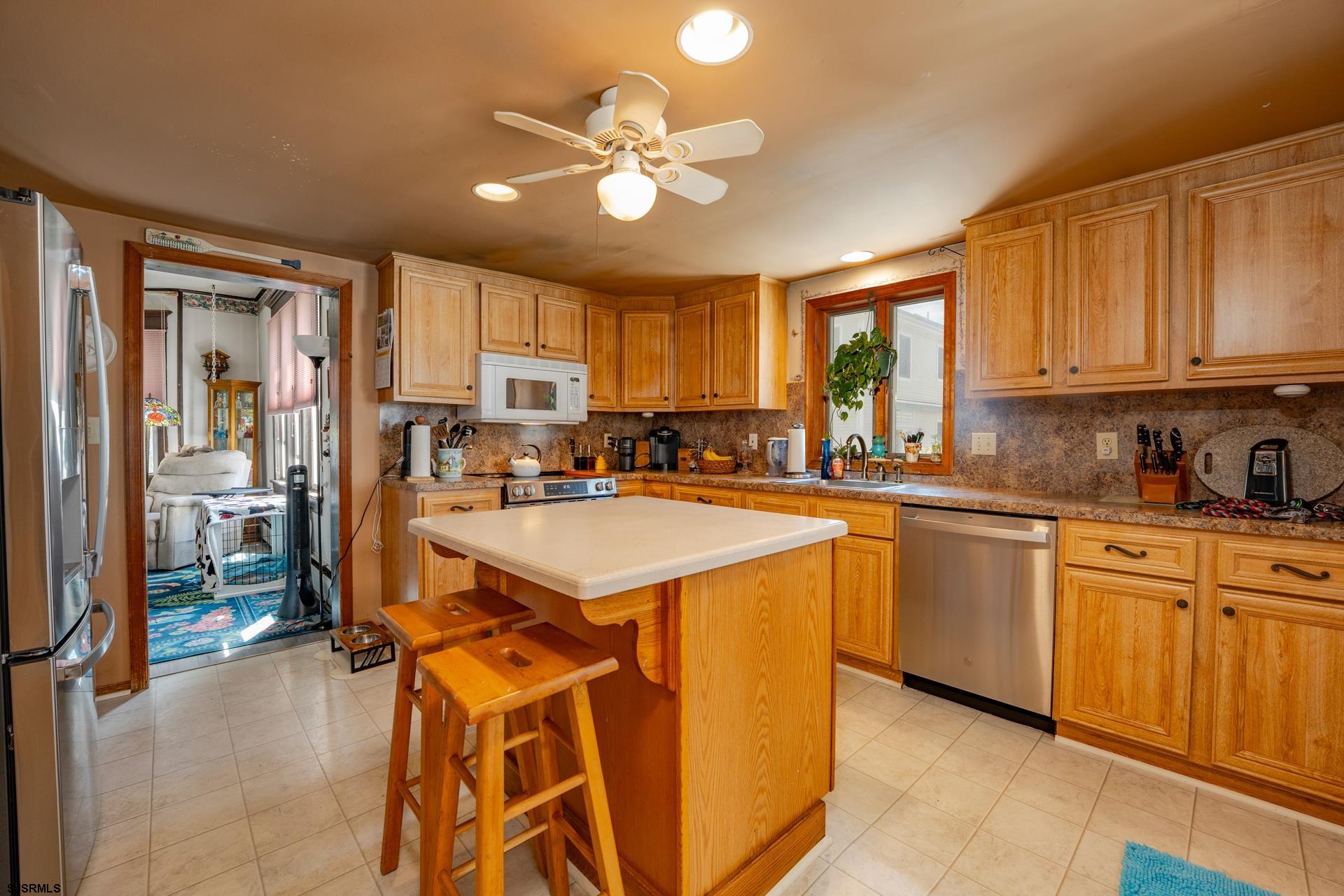 216 East Fern Road Wildwood Crest, NJ 08260 - Photo 32 of 93 a kitchen with stainless steel appliances kitchen island granite countertop a stove top oven a sink a dining table and chairs with wooden floor