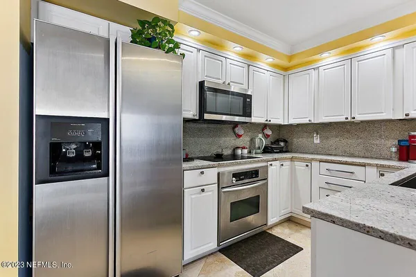 a kitchen with stainless steel appliances granite countertop a refrigerator a stove and a sink