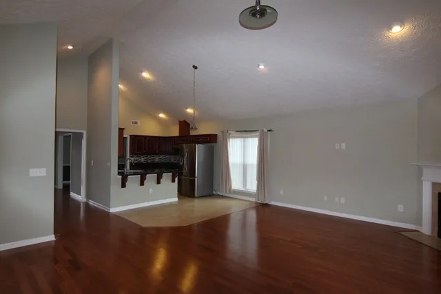 a view of an empty room with wooden floor and a ceiling fan