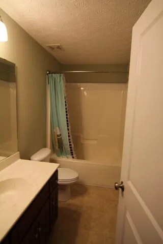 a bathroom with a granite countertop sink a toilet and shower