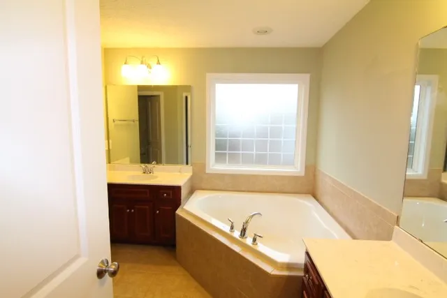 a bathroom with a tub sink and mirror
