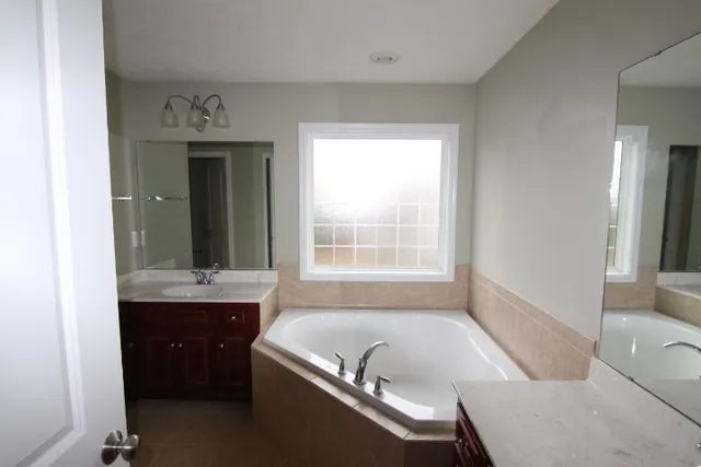 a bathroom with a tub a sink and a window