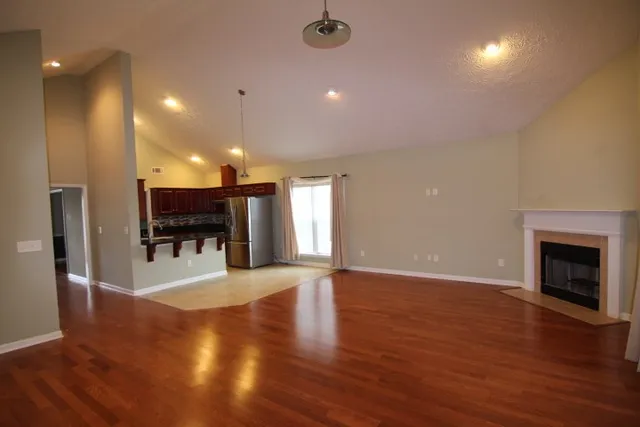 an empty room with wooden floor fireplace and windows