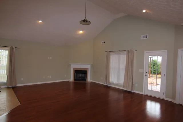 an empty room with wooden floor cabinet and windows