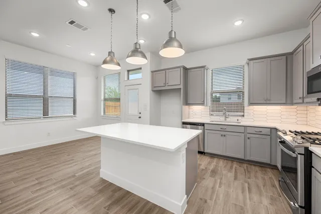 a large kitchen with kitchen island a large island in the center a sink stainless steel appliances and cabinets
