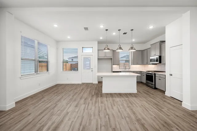 a large kitchen with stainless steel appliances kitchen island a large counter top and a wooden floors