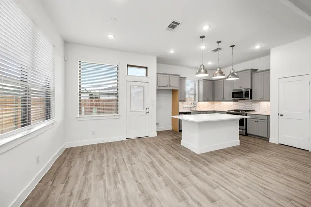 a large kitchen with a large counter top a sink stainless steel appliances and cabinets