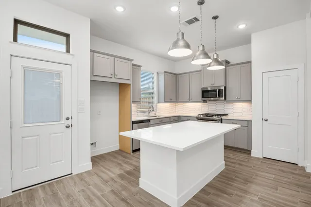 a large kitchen with stainless steel appliances a large counter top space wooden floor and center island