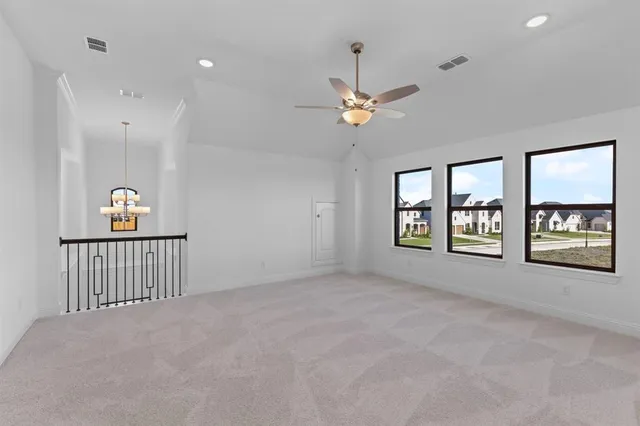 an empty room with chandelier fan and windows