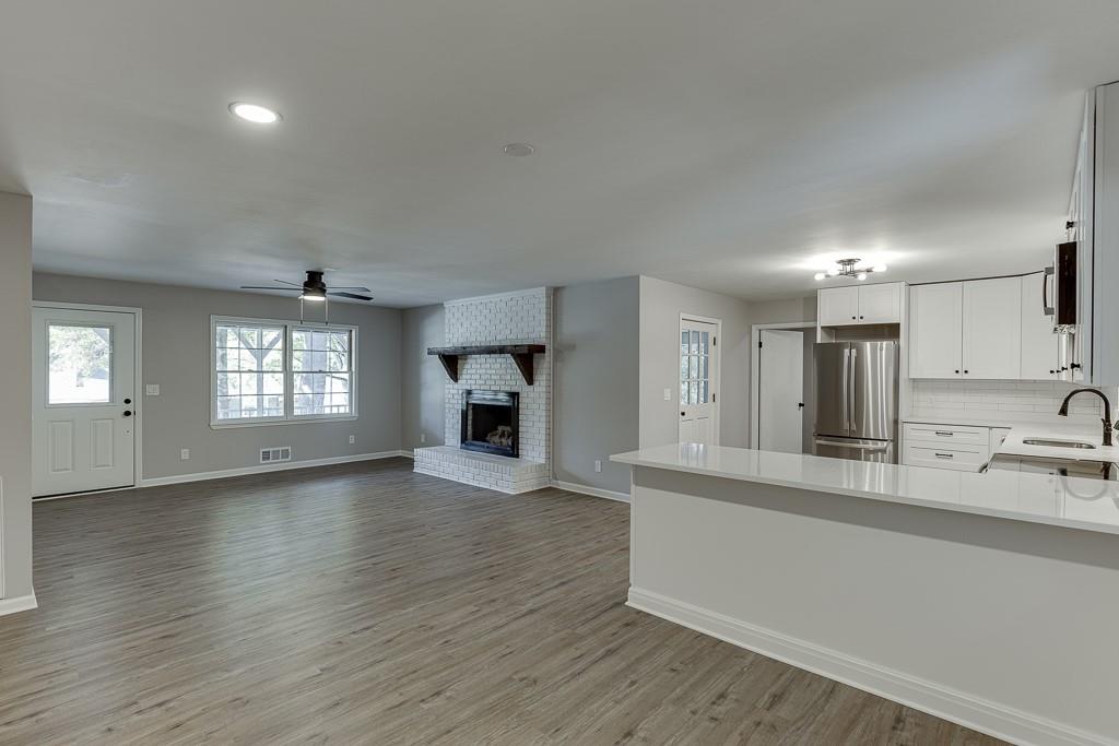 5837 Meadow View Lane Flowery Branch, GA 30542 - Photo 13 of 47 an empty room with wooden floor and a kitchen