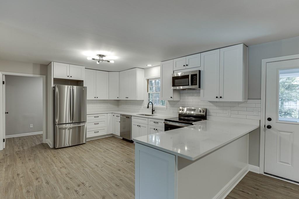 5837 Meadow View Lane Flowery Branch, GA 30542 - Photo 14 of 47 a kitchen that has a refrigerator a stove a sink and dishwasher with wooden floor