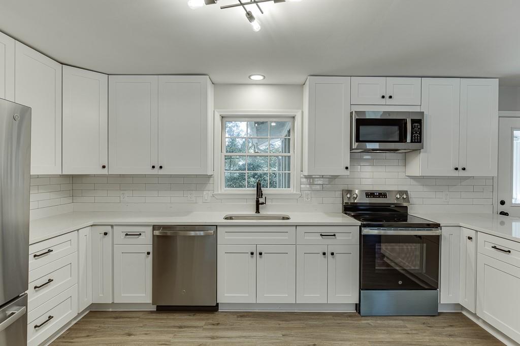 5837 Meadow View Lane Flowery Branch, GA 30542 - Photo 18 of 47 a kitchen with white cabinets and black appliances
