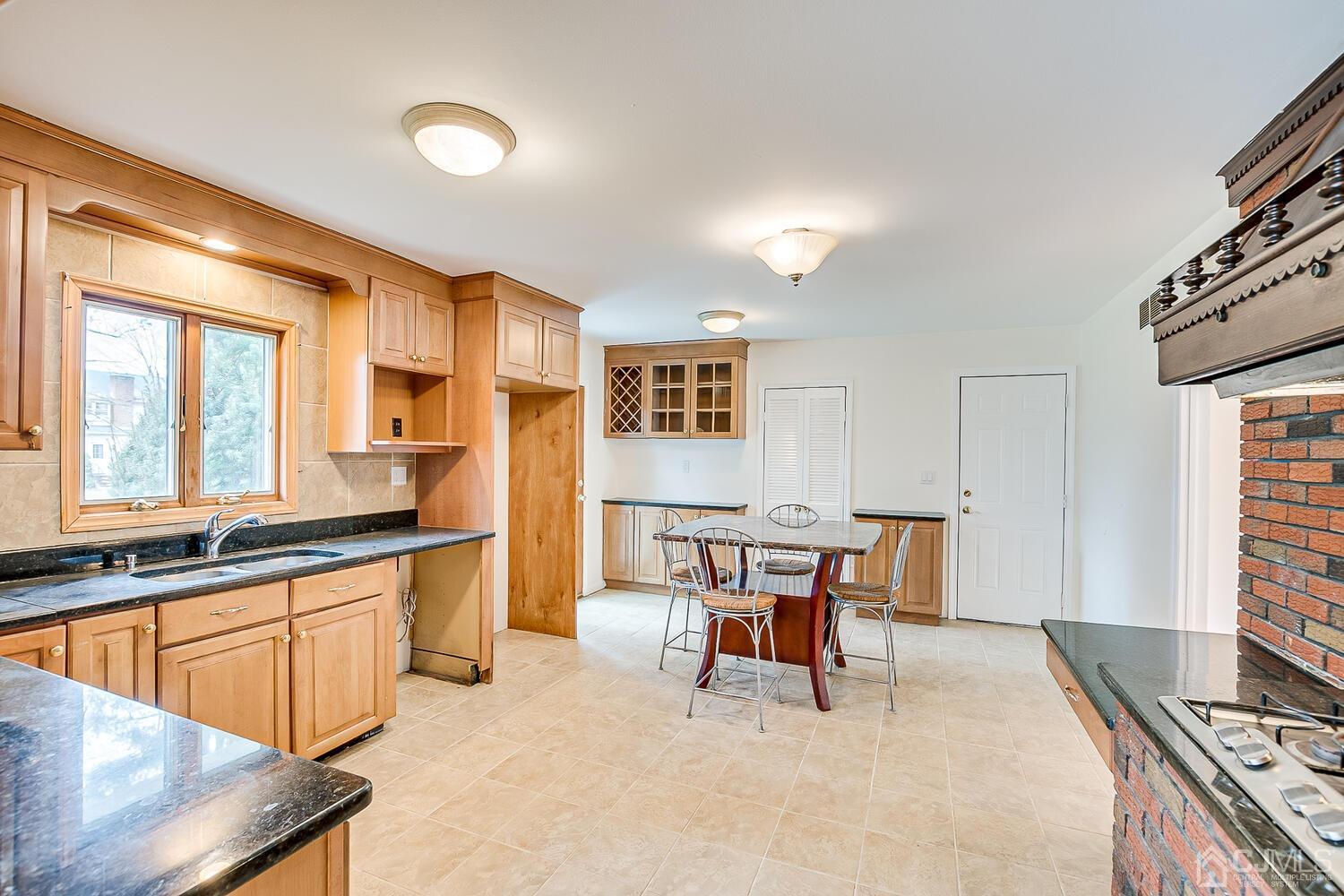 5 Robin Road Edison, NJ 08820 - Photo 11 of 43 a kitchen with stainless steel appliances kitchen island granite countertop a table chairs in it and a window