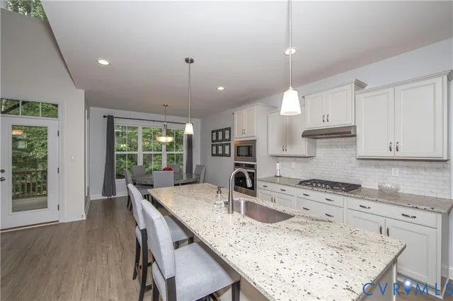 a kitchen with granite countertop a sink a center island a stove and a wooden cabinets