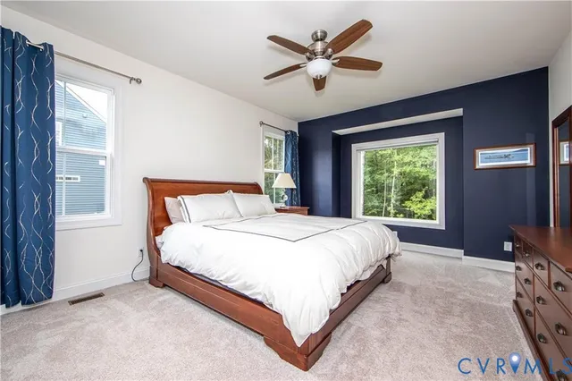a bedroom with a large bed and a flat tv screen on dresser