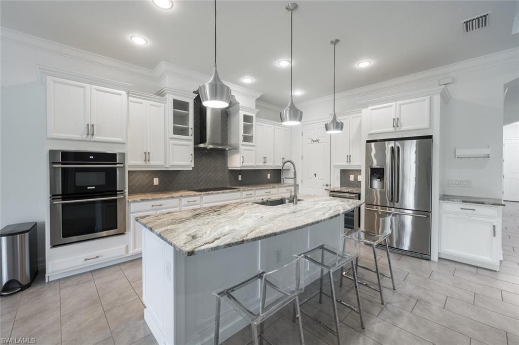 a kitchen with kitchen island a refrigerator a stove a sink and white cabinets