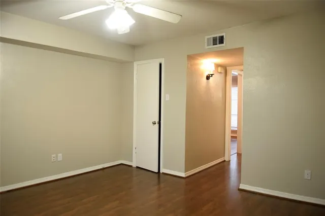 an empty room with wooden floor and a ceiling fan