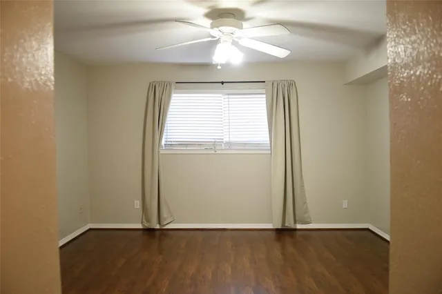 an empty room with wooden floor chandelier fan and windows