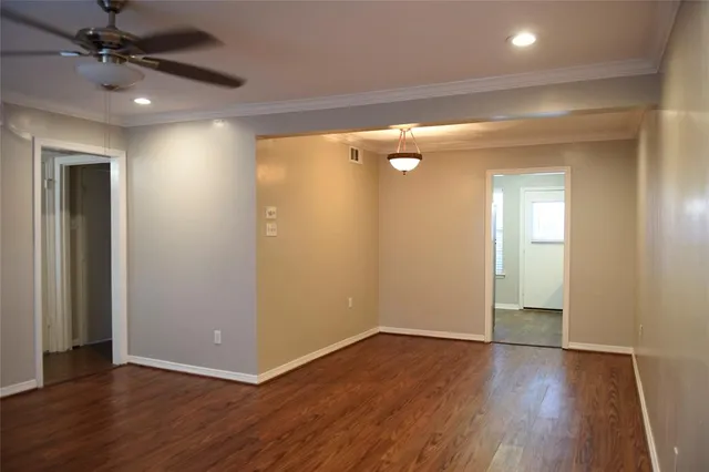an empty room with wooden floor and a ceiling fan