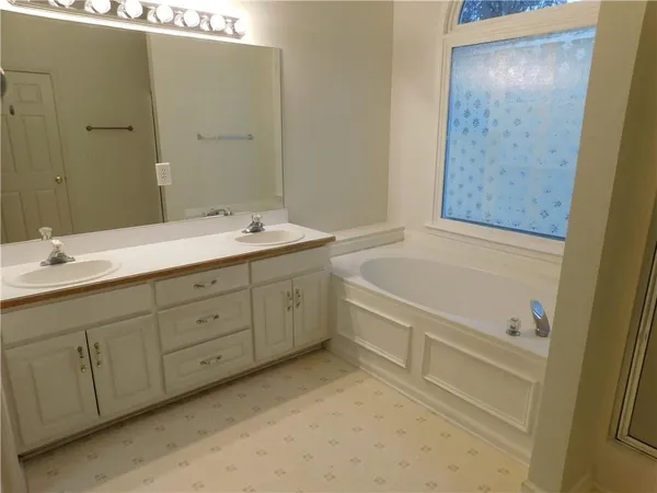 a bathroom with a double vanity sink and mirror with bathtub