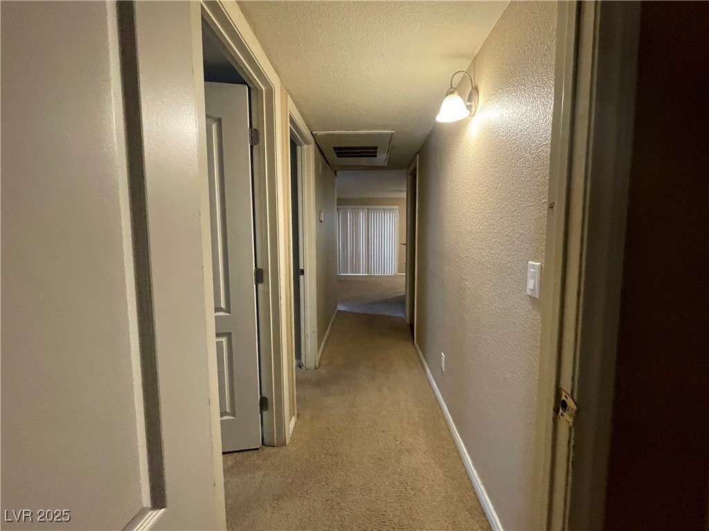 9325 West Desert Inn Road, Unit 149 Las Vegas, NV 89117 - Photo 16 of 20 Corridor featuring a textured wall, light colored carpet, and a textured ceiling