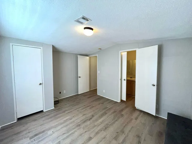 a view of an empty room with wooden floor and closet