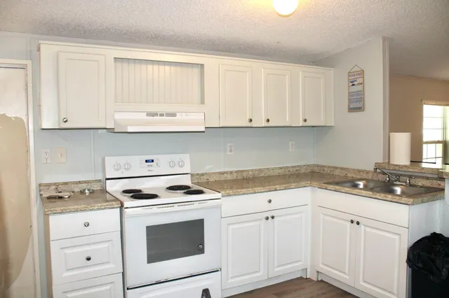 a kitchen with granite countertop white cabinets and white appliances