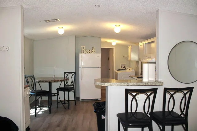 a kitchen with kitchen island a dining table chairs cabinets and stainless steel appliances