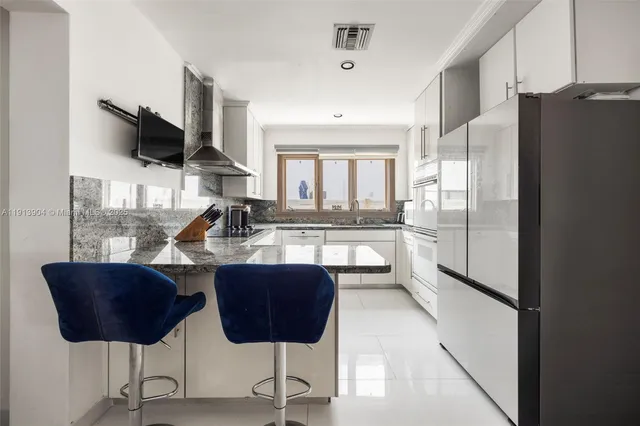 a kitchen with stainless steel appliances granite countertop a refrigerator a oven a sink with a dining table and chairs