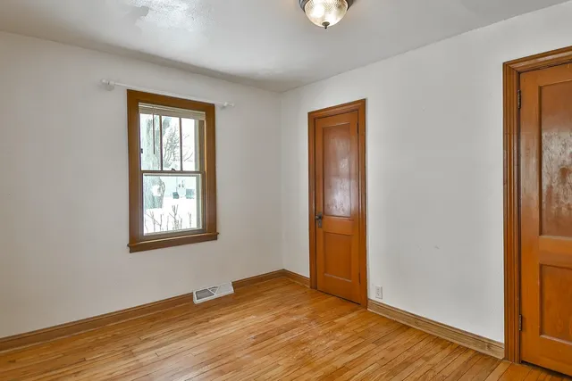 an empty room with wooden floor closet and windows