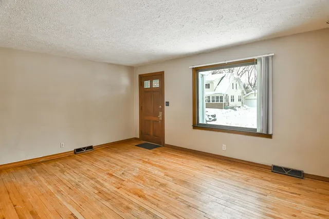 a view of an empty room with wooden floor and a window