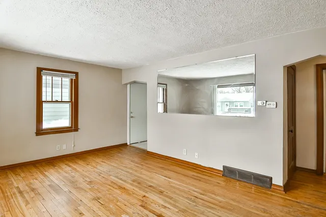 a view of an empty room with wooden floor and a window
