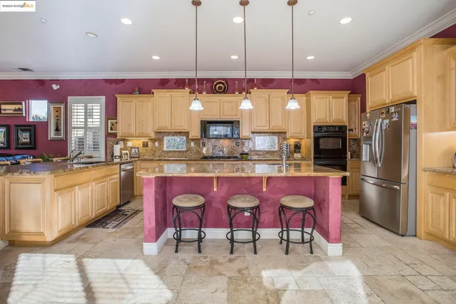 a kitchen with stainless steel appliances granite countertop a sink a stove a refrigerator and a refrigerator