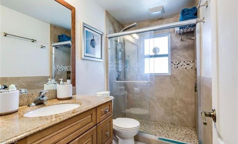 5325 23rd Place Southwest Naples, FL 34116 - Photo 6 of 10 Bathroom featuring a single vanity with a granite-style countertop, wood-finish cabinetry, and a chrome faucet