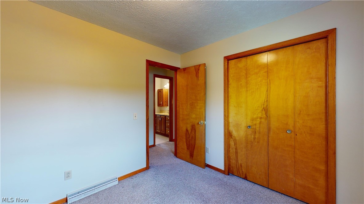 3394 Waterloo Road Mogadore, OH 44260 - Photo 22 of 40 Unfurnished bedroom featuring carpet, a closet, and a textured ceiling